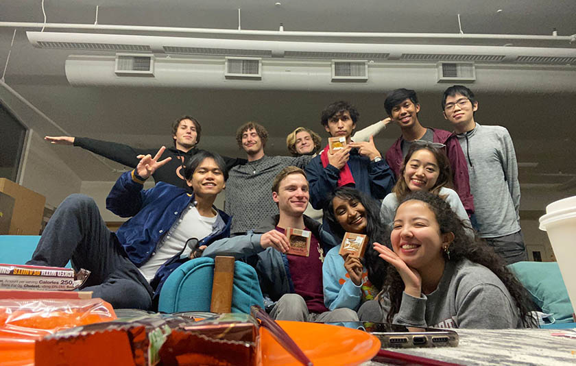 A group of students posing in a classroom with dim lighting