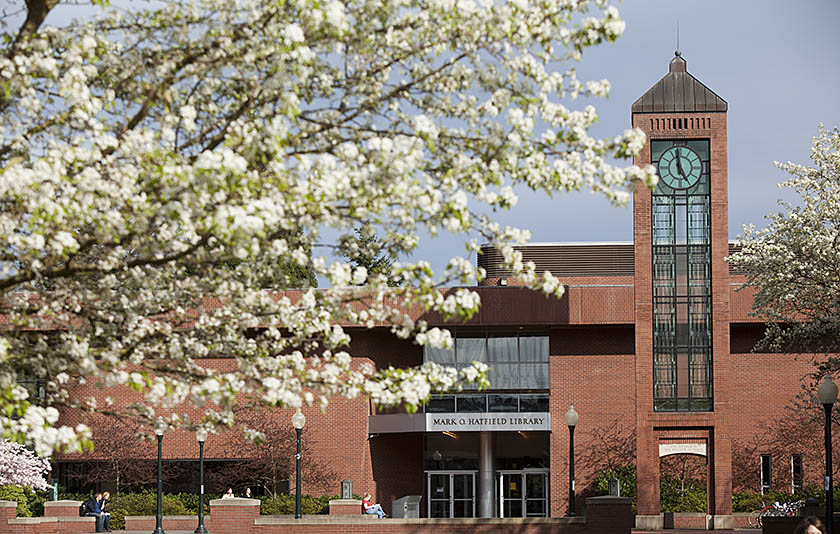 A tree with plenty of white flowers in front of a brick building at Willamette