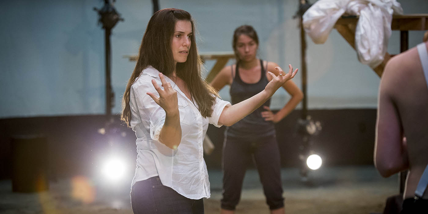 A theatre professor leads a rehearsal, demonstrating expressive movements to students on stage as part of a hands-on learning experience in a Willamette's Theatre program.