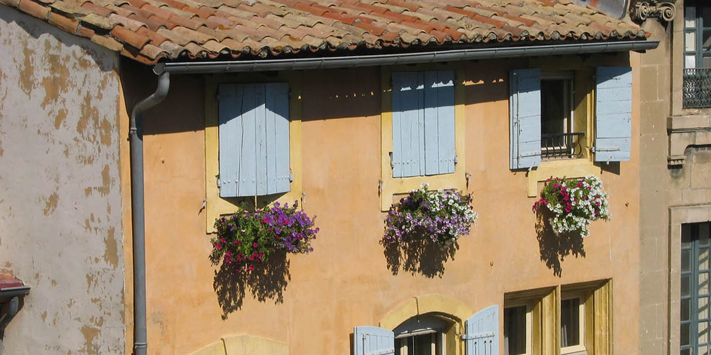 A picturesque French building with pastel-colored shutters and vibrant flower boxes, capturing the essence of French culture and architecture, often explored in French studies and study abroad programs.