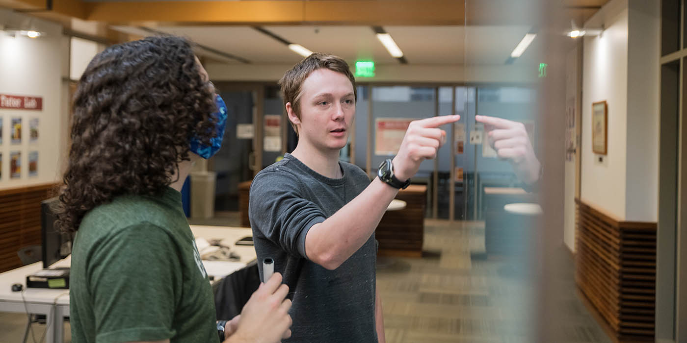 Two Willamette students study at a whiteboard in an academic hearth.