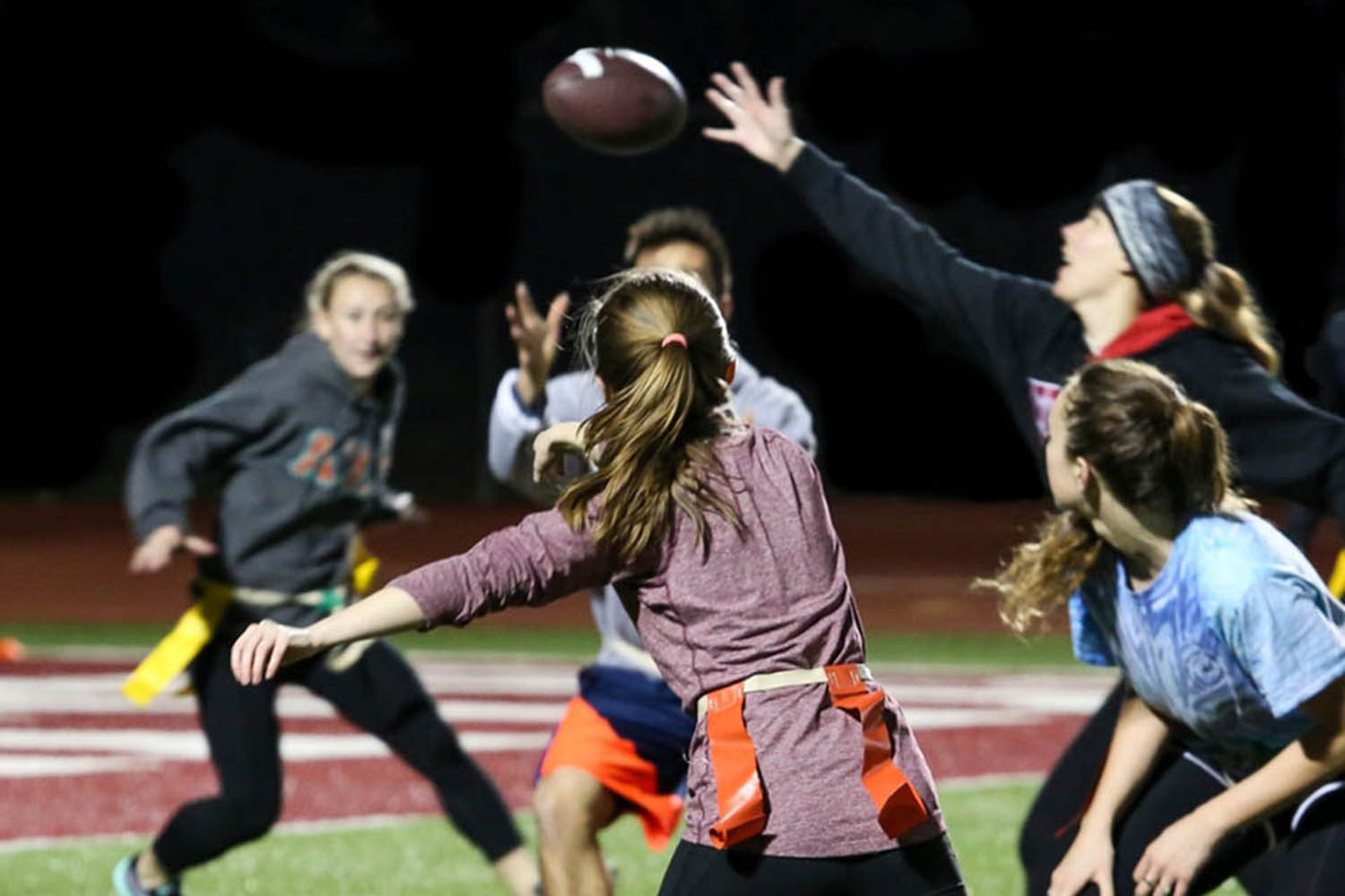 A group of female athletes playing flag football at night at Willamette