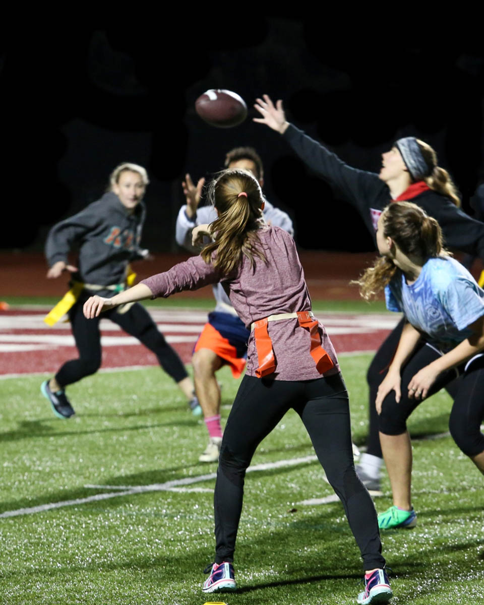 A group of female athletes playing flag football at night at Willamette