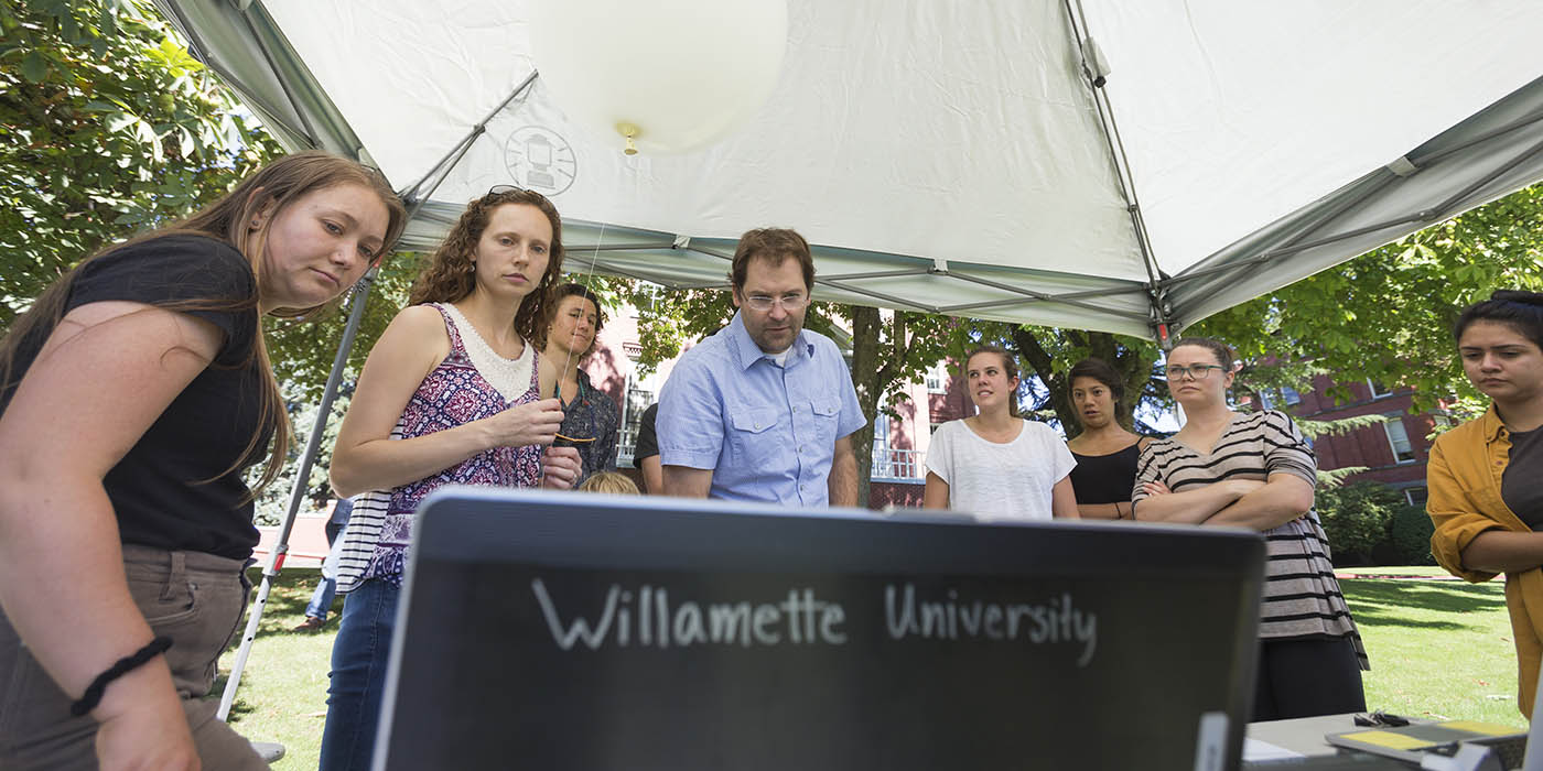 A group of Willamette students and a professor studying outside.