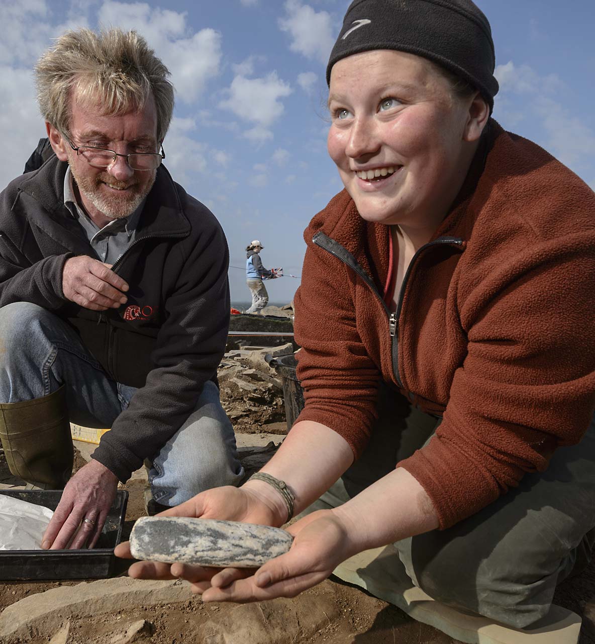 Professor looking at Willamette student holding a rock outside