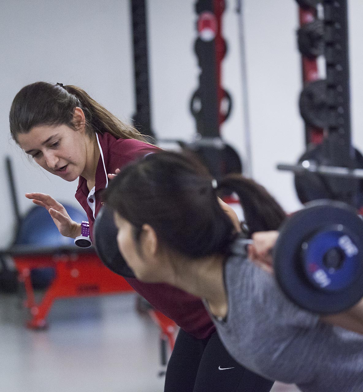 A professor assisting a Willamette student with a Barbell back squat