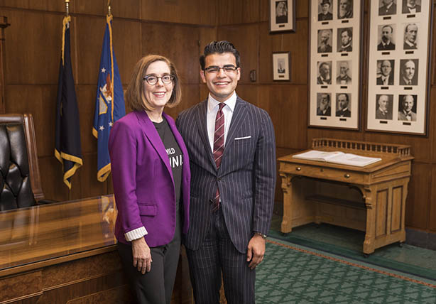 A student standing next to Governor Kate Brown in an Oregon government building