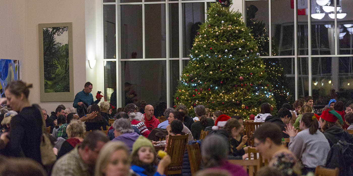People sitting around eating near a giant Christmas tree