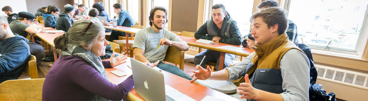 A group of students chatting with a professor