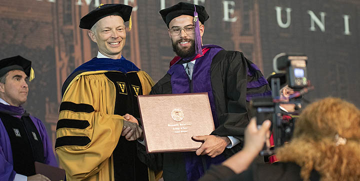A student getting their degree and shaking hands with another person