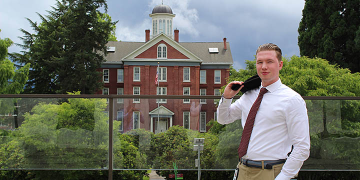 A student in business attire standing outside of a historic building