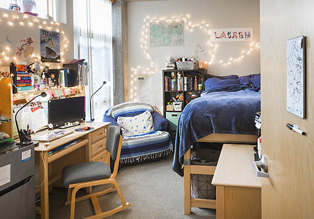 An example dorm room featuring light, chairs, a bed, and a lot of wood furniture