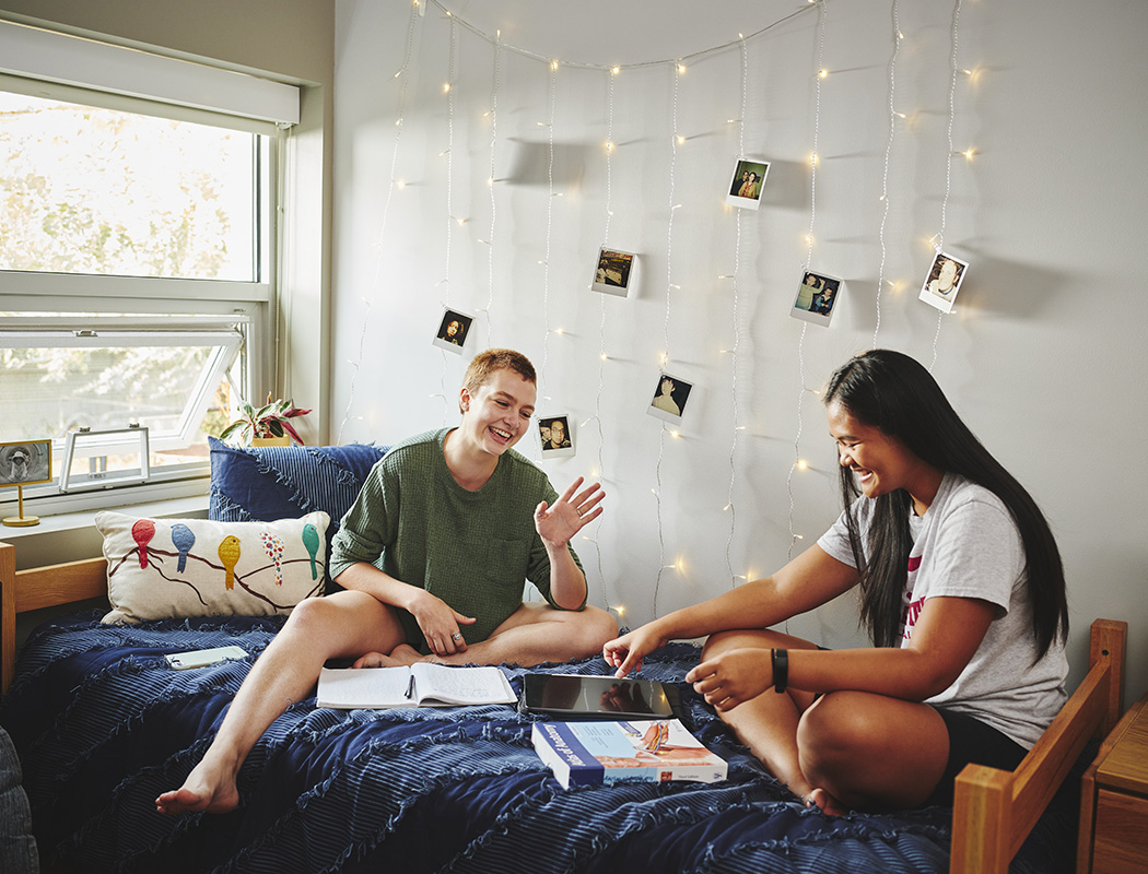Two students bonding while sitting on a bed in a Willamette dorm room