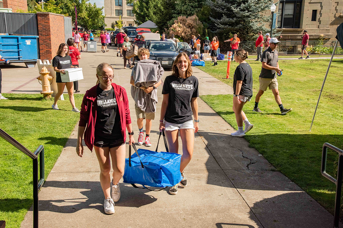 Students moving in with two students at the front lifting a blue bag