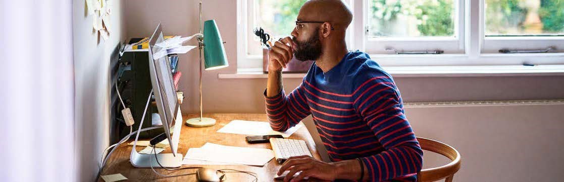 A man looking at a computer screen in a stripped shirt