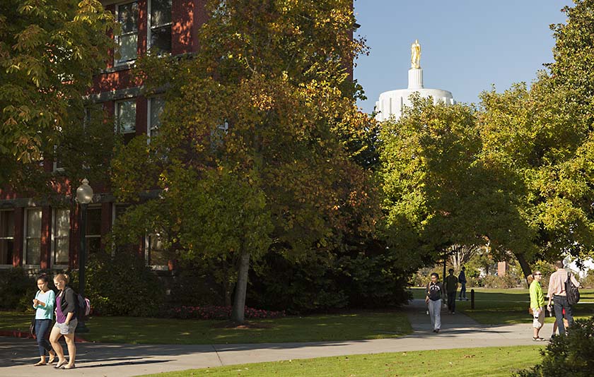 A paved walking path at Willamette with the State Capitol Gold Man behind it