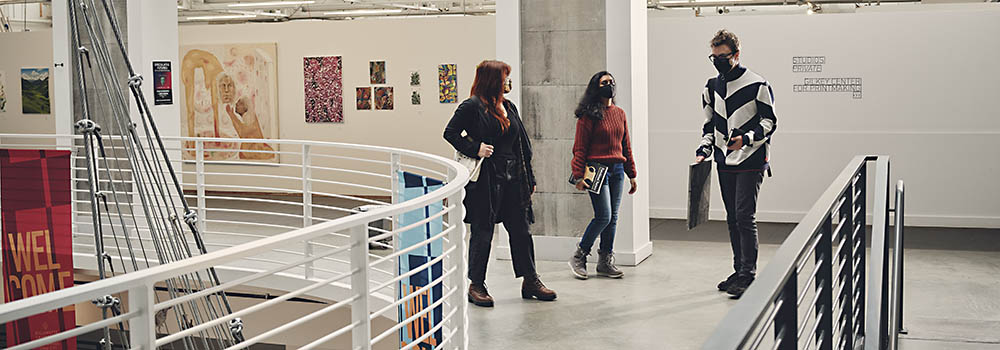Three students walking near a staircase within PNCA's Portland campus
