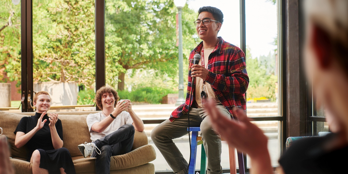 A student with a microphone speaking to a room of other students